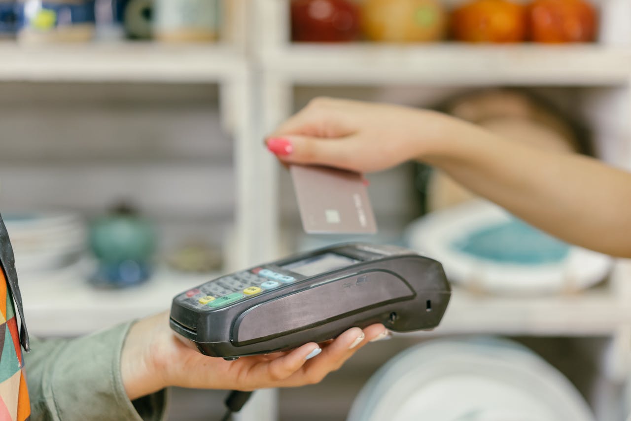 A person making a contactless payment with a credit card on a card reader.
