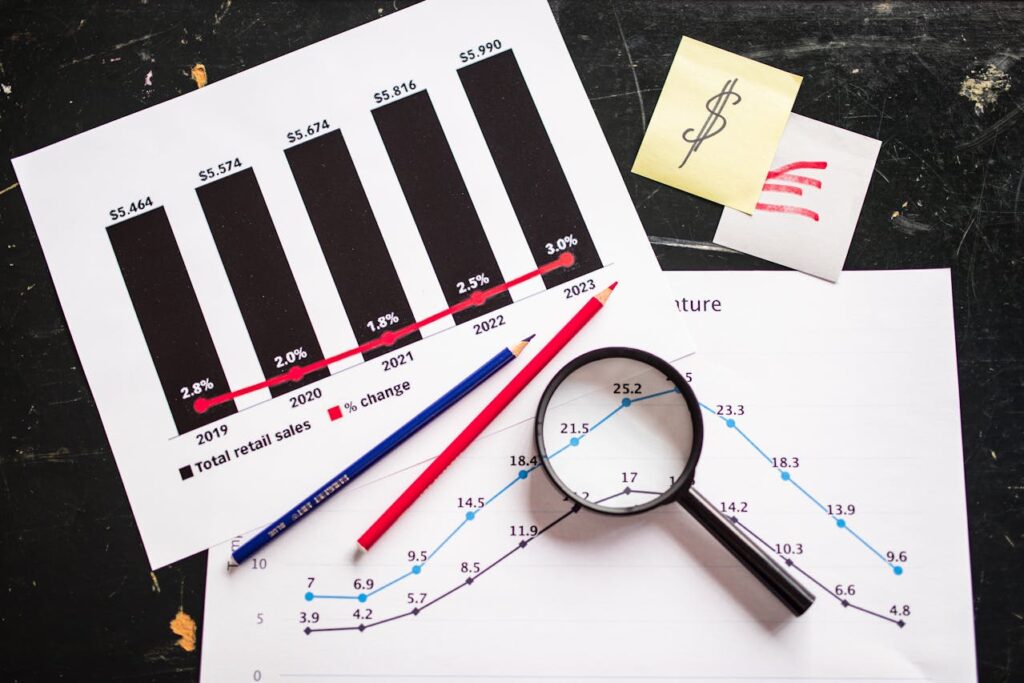 A magnifying glass over financial documents with sales graphs and data analysis.